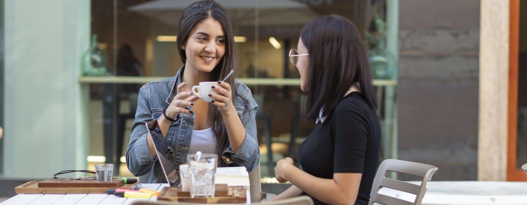 two woman sitting at a table drinking coffee